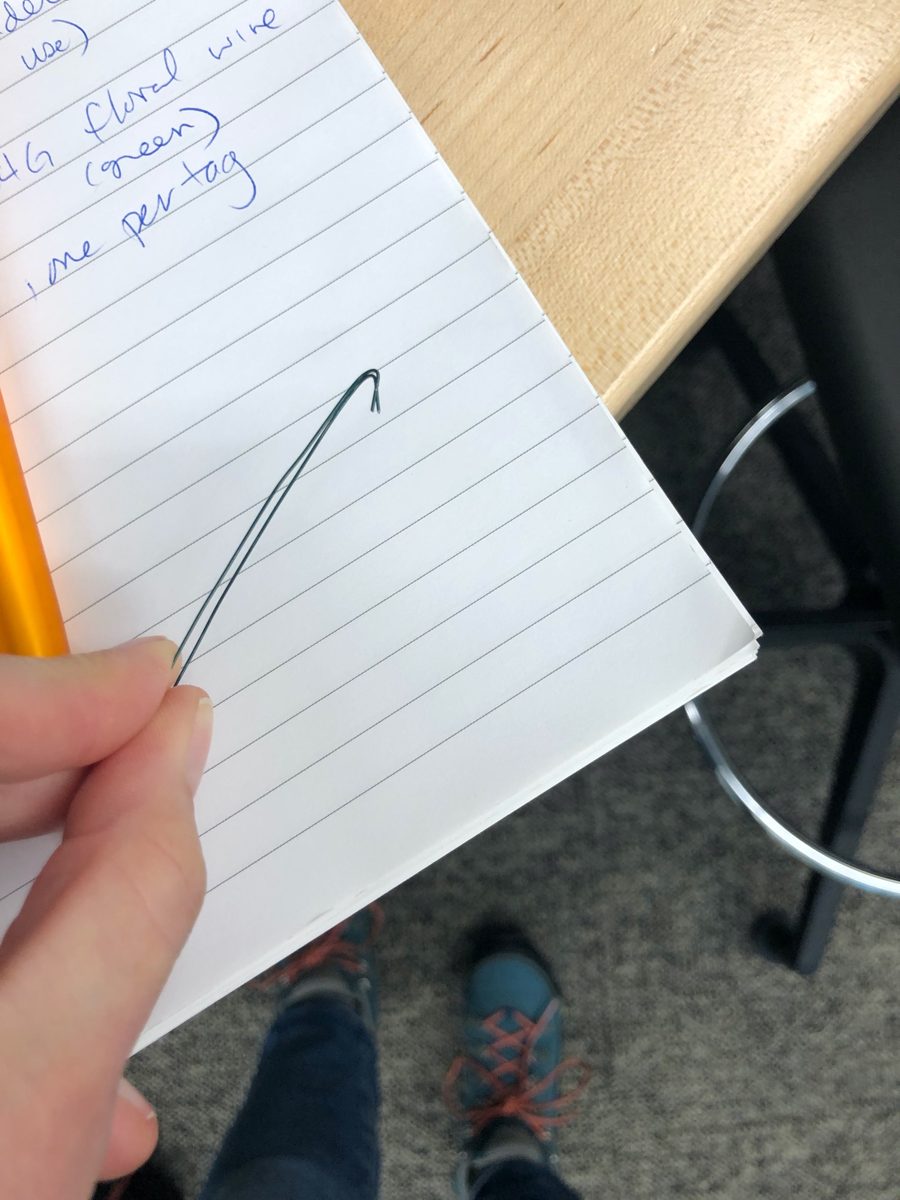 A length of green floral wire folded in half with hooks bent into the ends