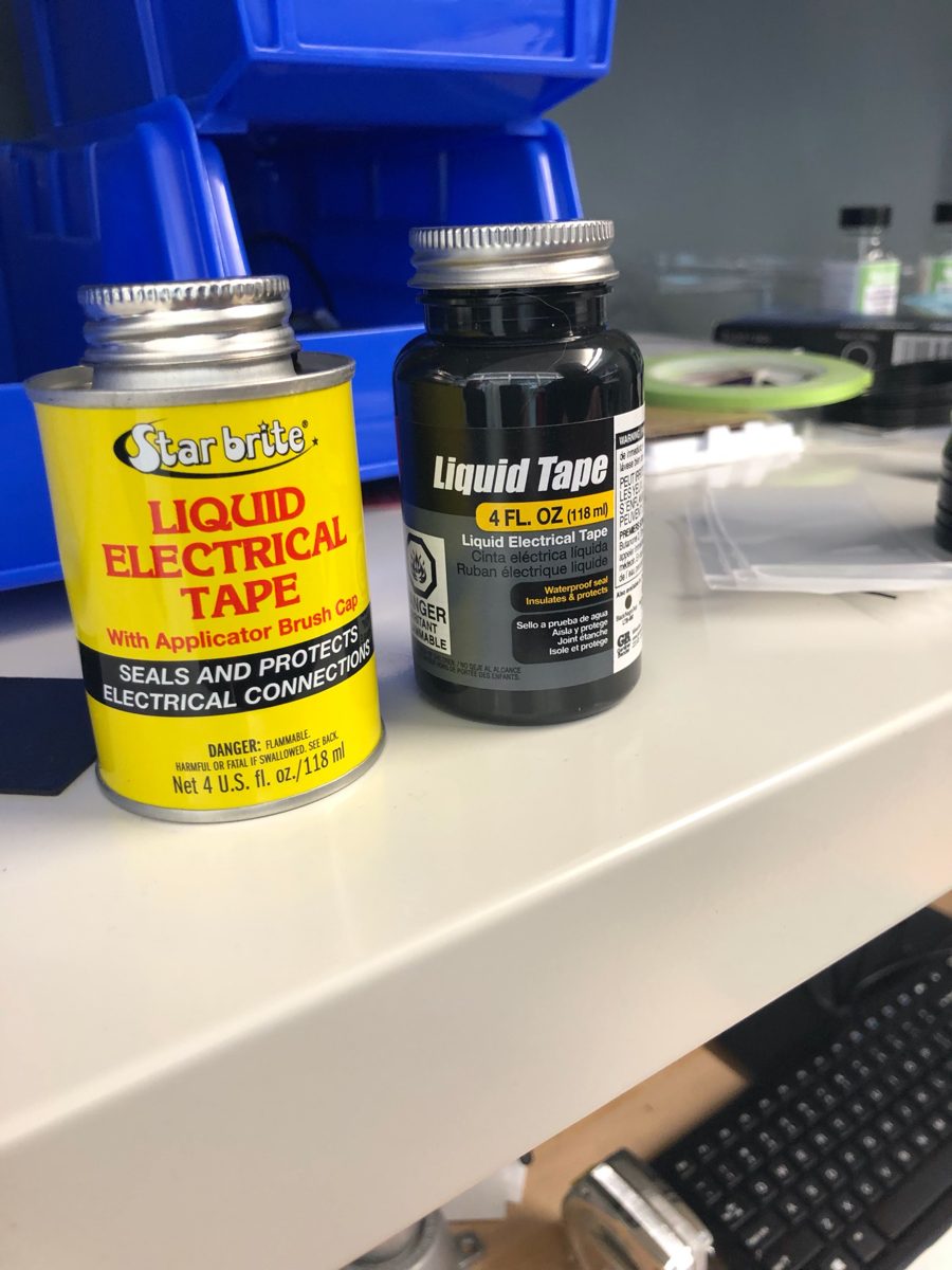 Two containers of liquid electrical tape on a shelf