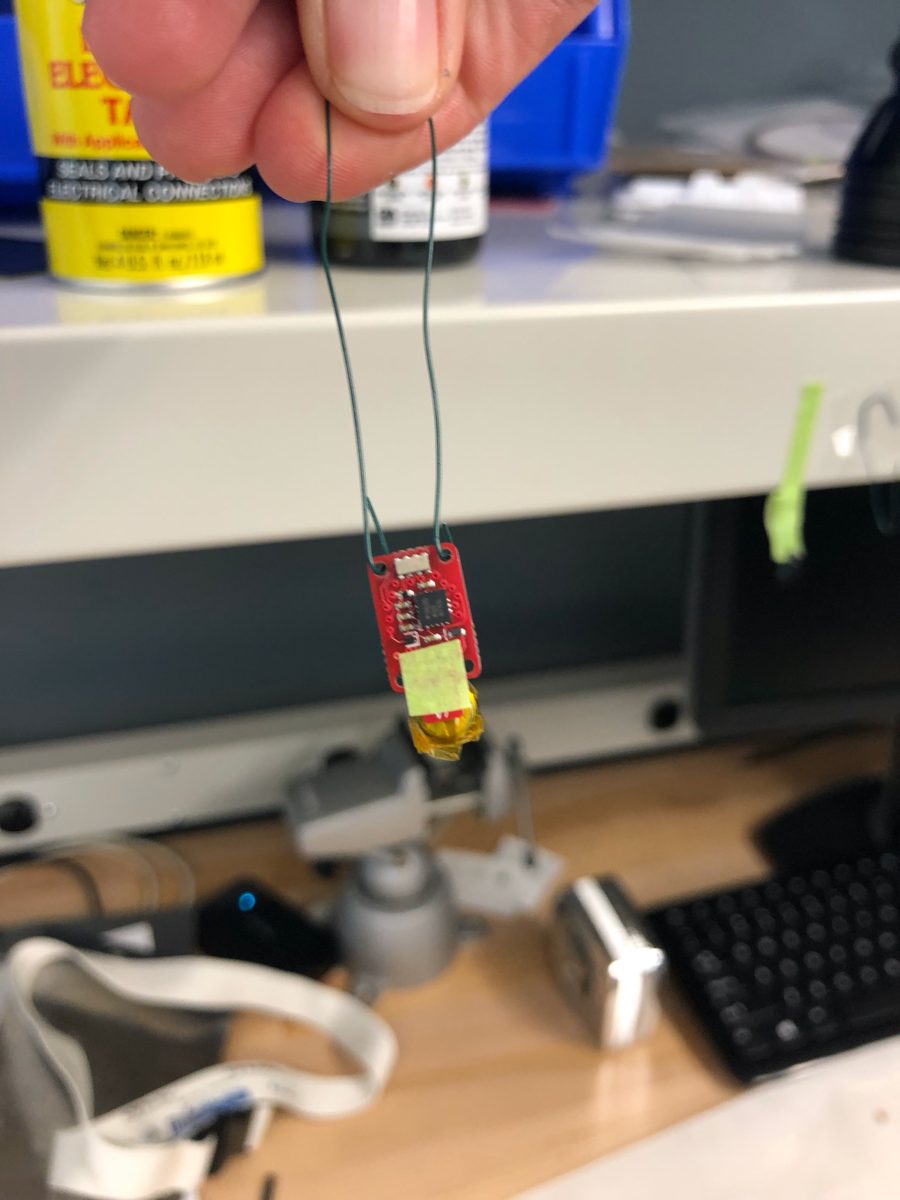 A tag hanging from its wire hanger with the contacts masked and the battery pointing down